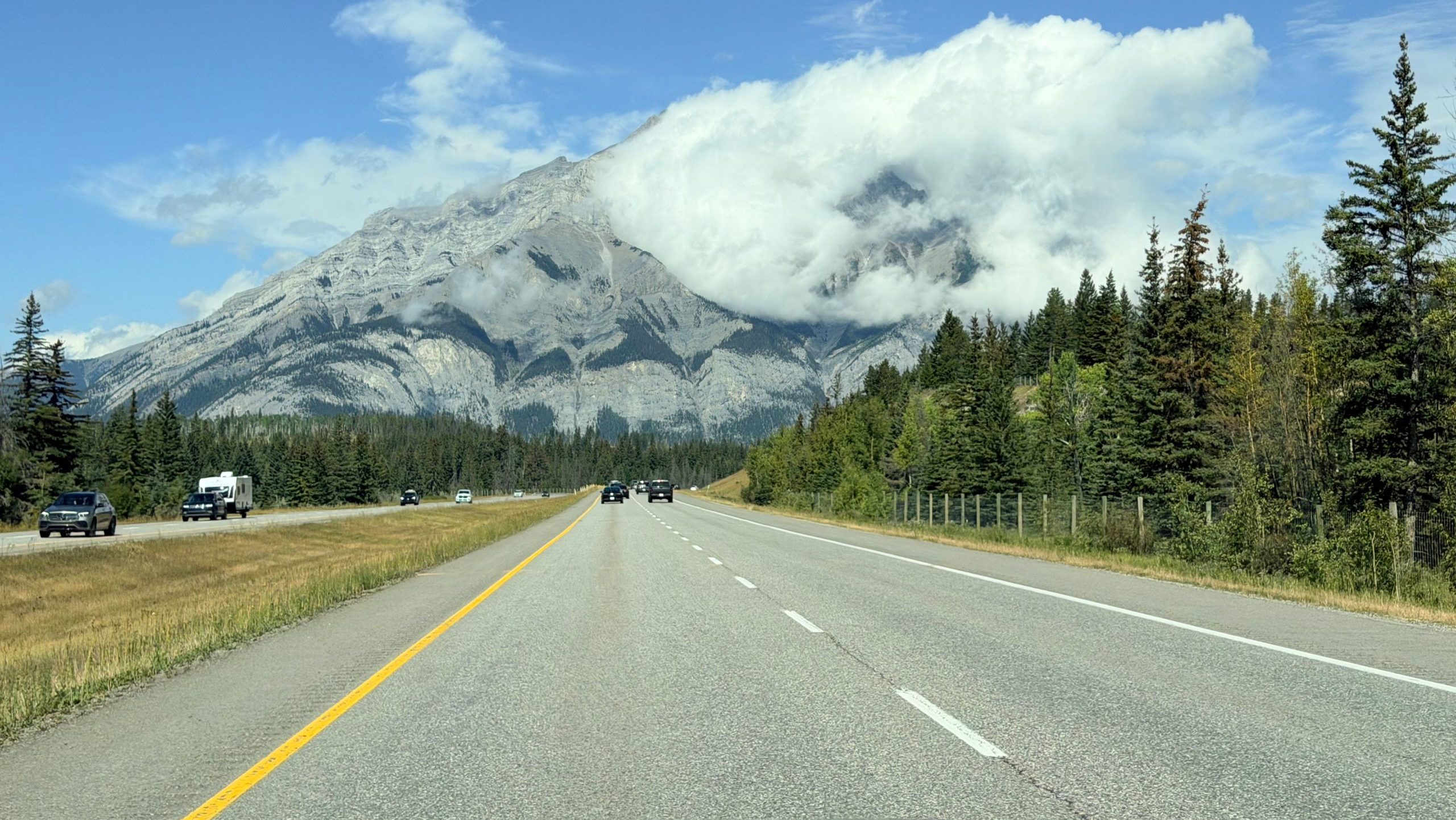 Scenic view of the Icefields Parkway highway winding through the Canadian Rockies surrounded by pine forests and snow-capped peaks in Banff National Park Canada