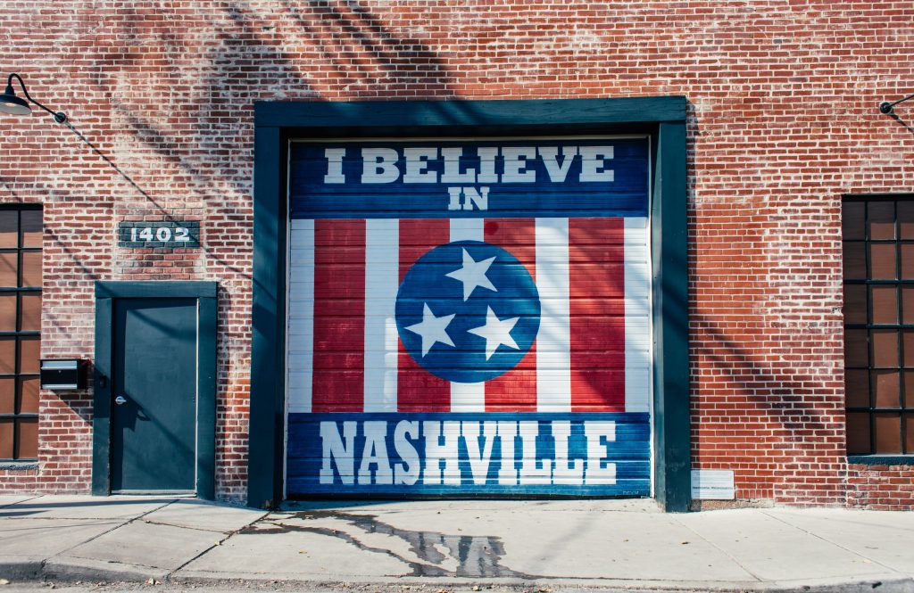 "I Believe in Nashville" mural on a brick building exterior with a door and windows in Nashville, Tennessee